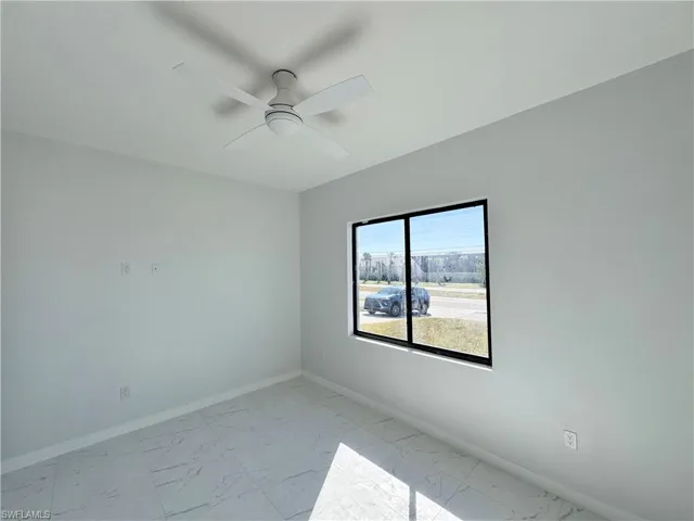 Spare room featuring light marble finish floors and ceiling fan