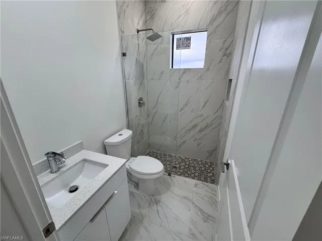 Bathroom with vanity, a marble finish shower, and light marble finish flooring