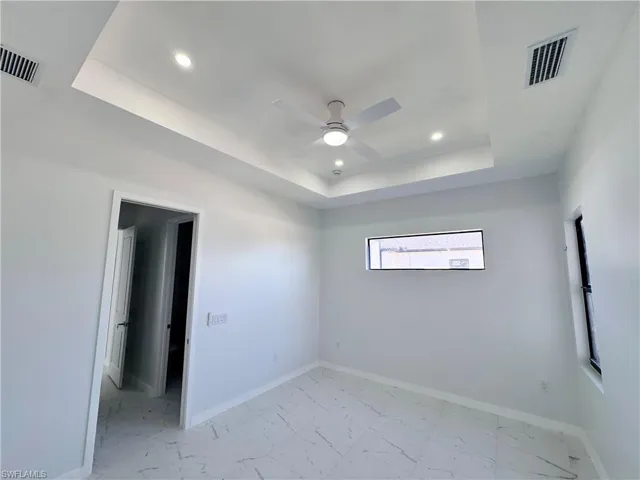Spare room with recessed lighting, ceiling fan, light marble finish flooring, and a raised ceiling