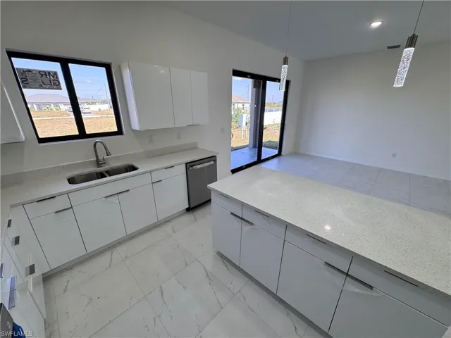 Kitchen with modern cabinets, decorative light fixtures, light stone counters, stainless steel dishwasher, and light marble finish floors
