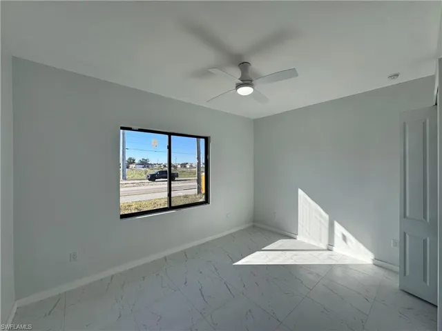 Unfurnished room featuring light marble finish flooring and a ceiling fan