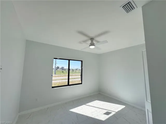 Unfurnished room with light marble finish flooring and ceiling fan