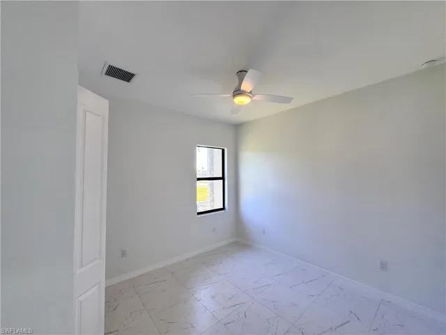 Spare room with light marble finish floors and ceiling fan