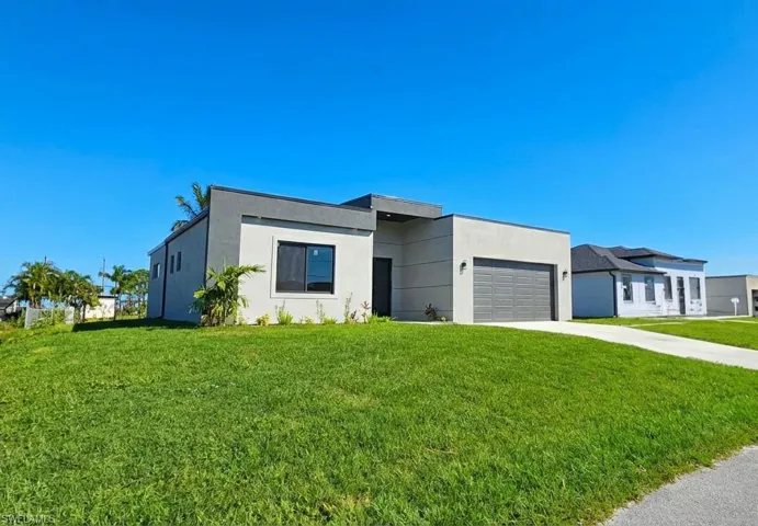 Modern home with driveway, a front yard, stucco siding, and an attached garage