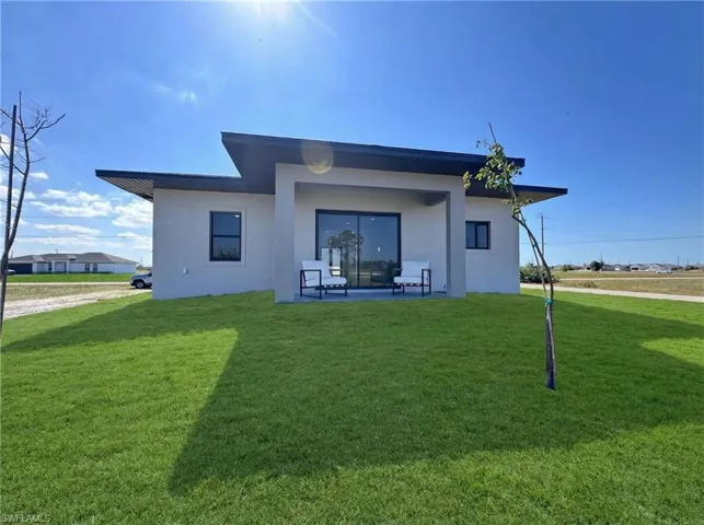 Back of house with a yard, stucco siding, and a patio area