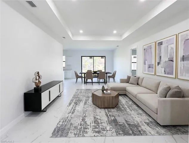 Living area with recessed lighting, a raised ceiling, and light marble finish floors