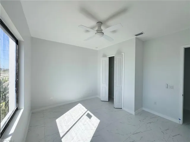 Unfurnished bedroom with a ceiling fan and light marble finish flooring