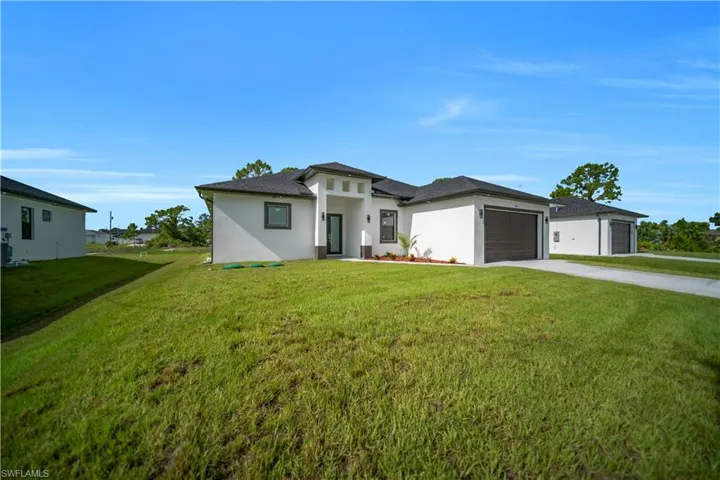 Prairie-style house with concrete driveway, a garage, a front yard, and stucco siding