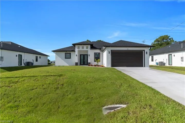 Prairie-style home featuring stucco siding, a garage, driveway, and a front yard