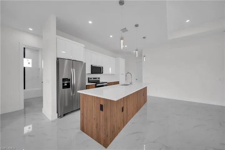 Kitchen with stainless steel appliances, light marble finish floors, modern cabinets, white cabinets, and recessed lighting