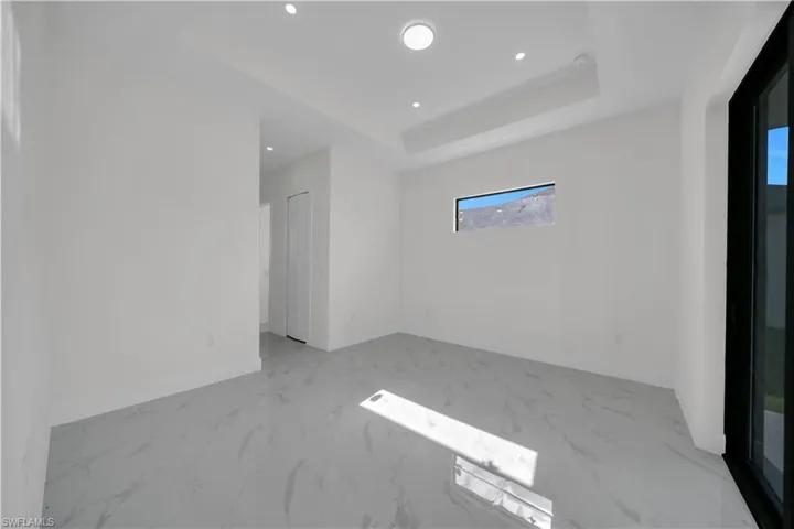 Unfurnished room with light marble finish flooring, recessed lighting, and a tray ceiling