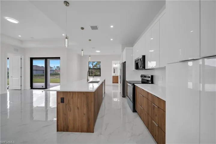 Kitchen featuring modern cabinets, stainless steel appliances, white cabinetry, light countertops, and recessed lighting