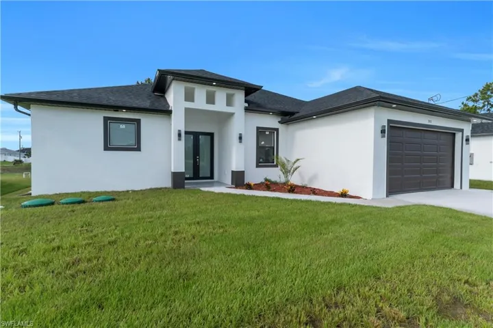 Prairie-style home featuring french doors, a garage, driveway, a front yard, and stucco siding