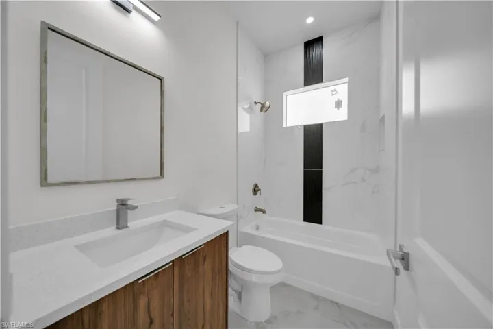 Bathroom with vanity,  shower combination, marble finish floors, and recessed lighting