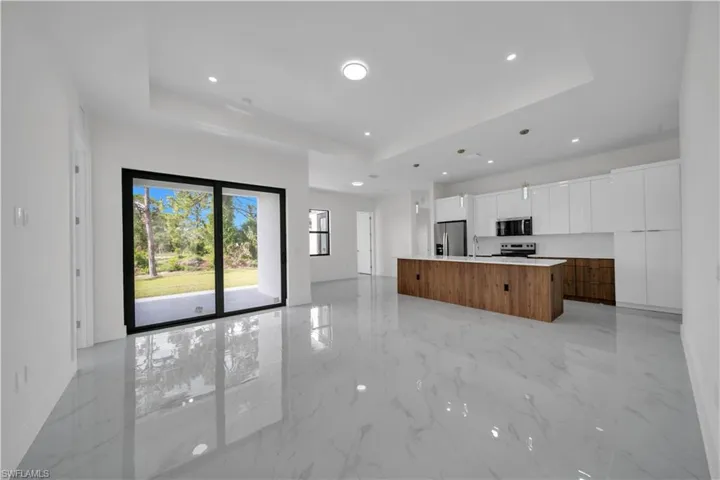Kitchen featuring appliances with stainless steel finishes, modern cabinets, a raised ceiling, a center island, and recessed lighting