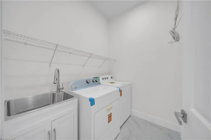 Washroom with independent washer and dryer, cabinet space, and light marble finish floors