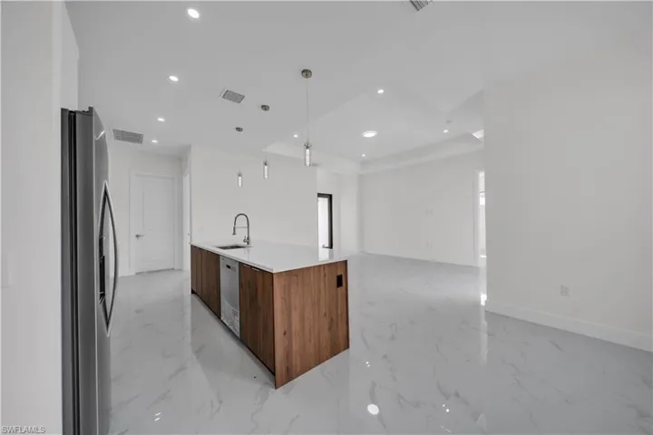 Kitchen with appliances with stainless steel finishes, light marble finish flooring, modern cabinets, open floor plan, and recessed lighting