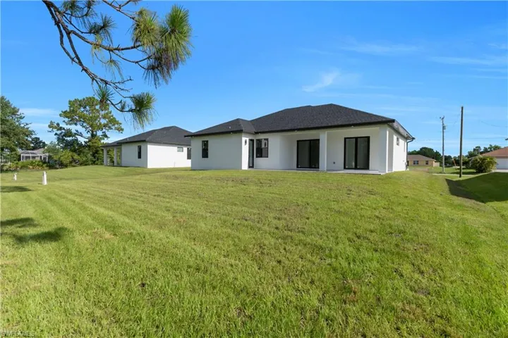 Back of house with a lawn and stucco siding