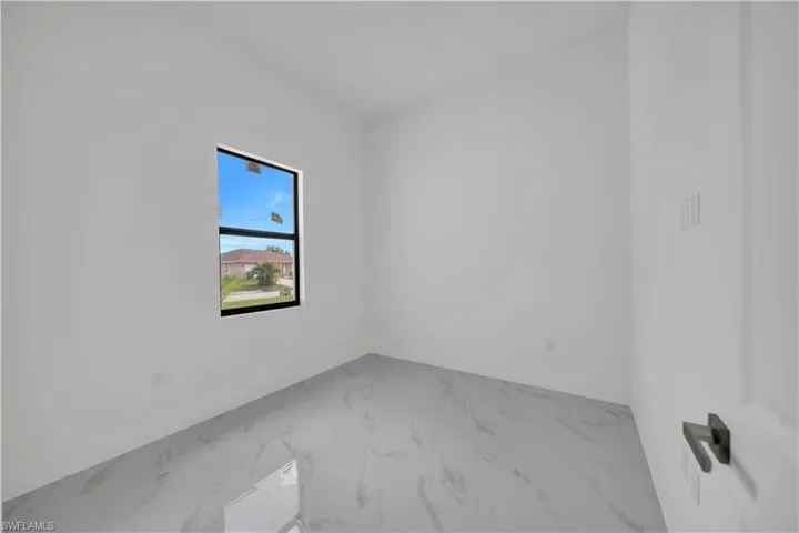 Spare room with marble look tile flooring and baseboards