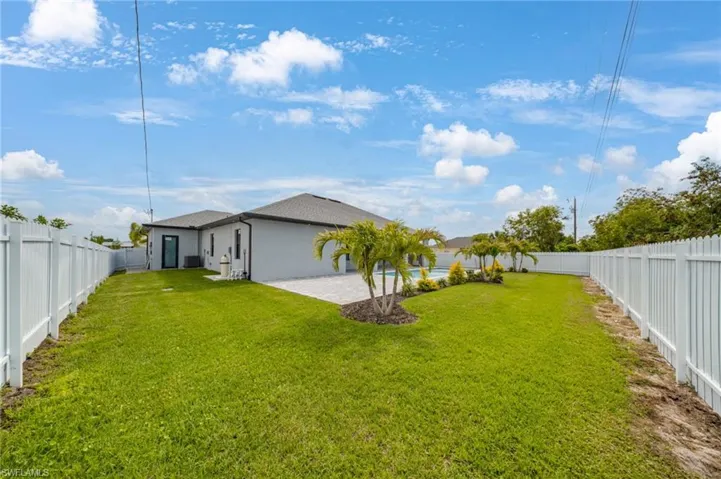 Expansive green lawn framed by a white privacy fence