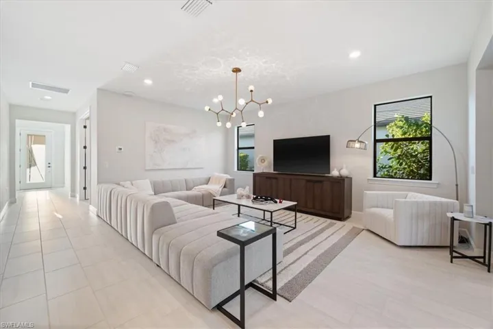 Kitchen featuring visible vents, light countertops, appliances with stainless steel finishes, wall chimney range hood, and an island with sink