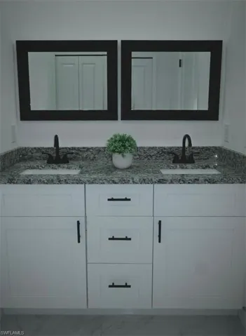 Bathroom featuring light marble finish floors and double vanity