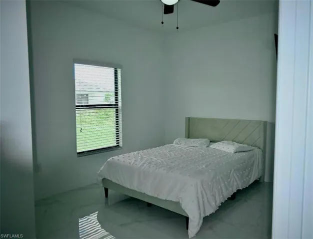 Bedroom with marble look tile flooring and a ceiling fan