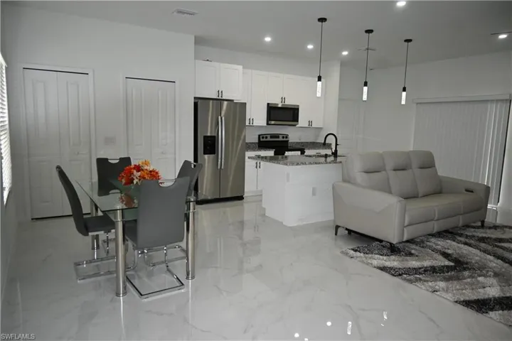 Kitchen with stainless steel appliances, open floor plan, decorative light fixtures, recessed lighting, and dark stone countertops