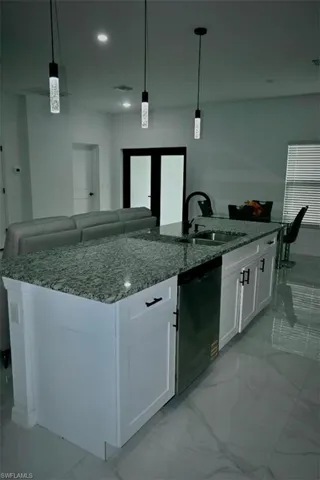Kitchen with light stone counters, light marble finish floors, hanging light fixtures, white cabinetry, and recessed lighting