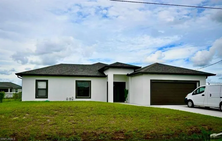 View of front of home with stucco siding, a garage, a front lawn, and concrete driveway