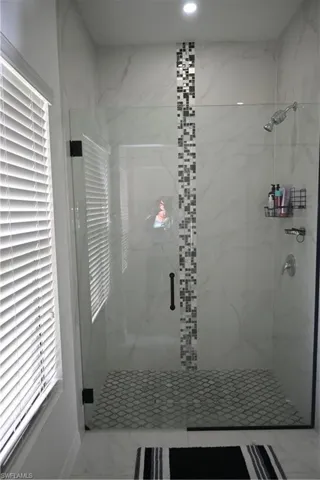 Full bath with a marble finish shower