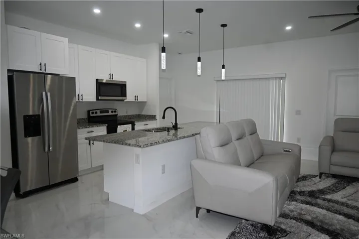 Kitchen featuring open floor plan, appliances with stainless steel finishes, dark stone countertops, recessed lighting, and pendant lighting