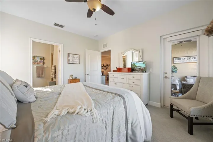 Bedroom featuring light carpet, ceiling fan, and ensuite bathroom
