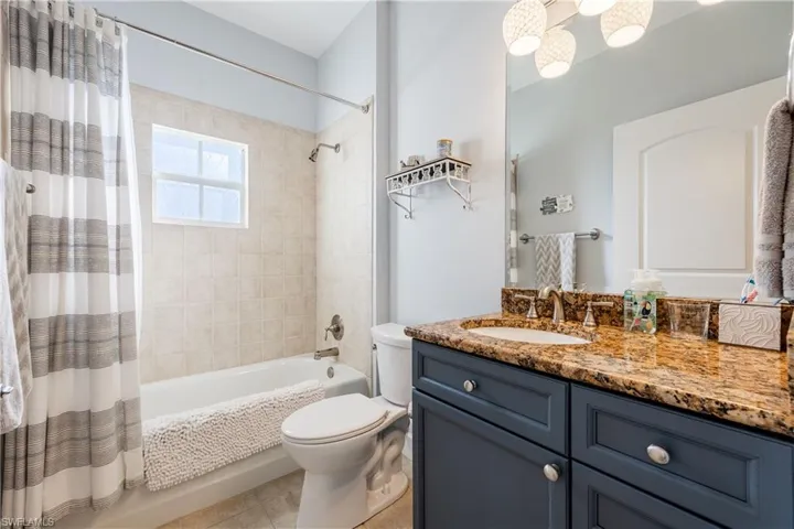 Full bathroom with shower / tub combo, vanity, and light tile patterned flooring