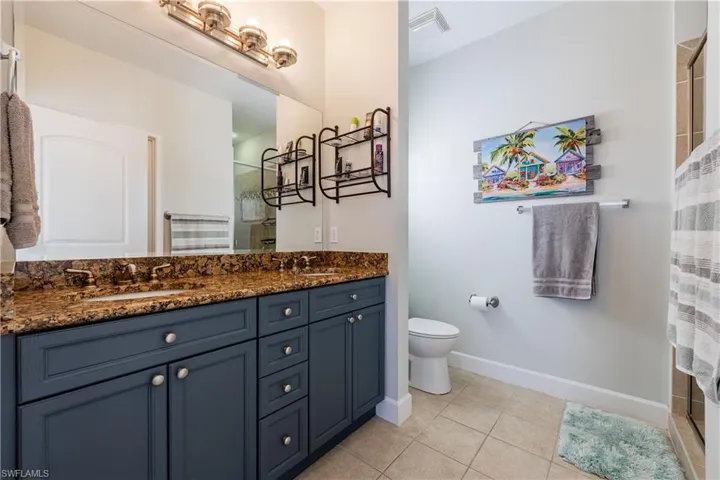Bathroom featuring double vanity, light tile patterned floors, and walk in shower