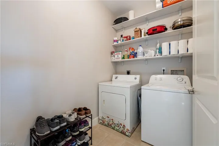 Washroom featuring light tile patterned flooring and washing machine and dryer