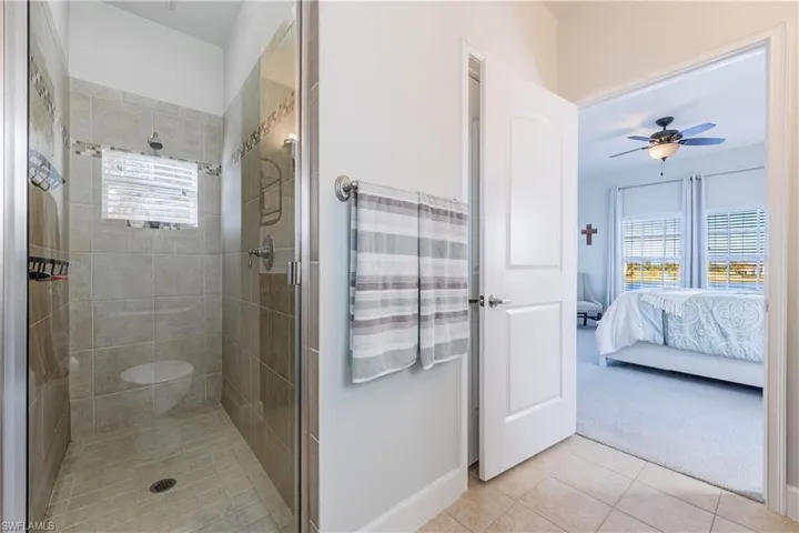 Ensuite bathroom with healthy amount of natural light, light tile patterned floors, and a stall shower