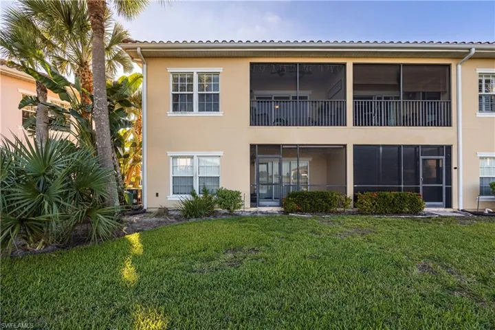 Back of property with a balcony, a sunroom, stucco siding, and a yard