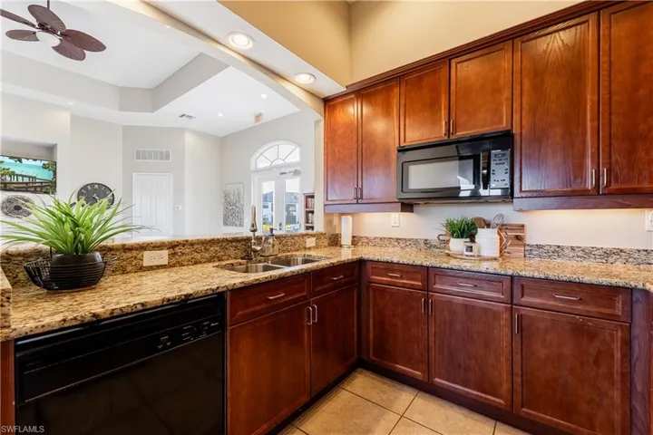Kitchen with black appliances, light stone countertops, light tile patterned floors, recessed lighting, and a ceiling fan