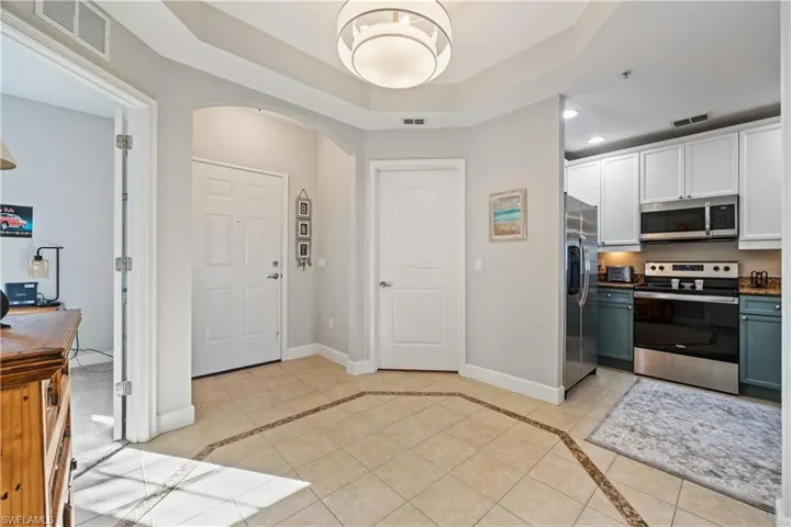 Foyer entrance with arched walkways, light tile patterned floors, a tray ceiling, inlaid floor details, and recessed lighting