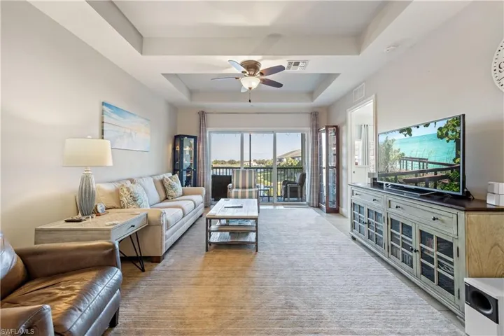 Living area with a raised ceiling and a ceiling fan