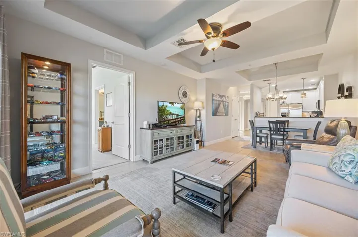 Tiled living room with a tray ceiling, a ceiling fan, and a chandelier