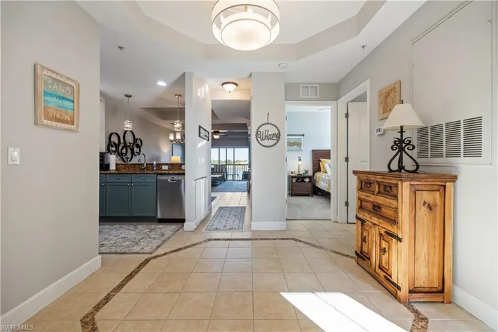Hallway with a raised ceiling, inlaid floor details, and light tile patterned flooring