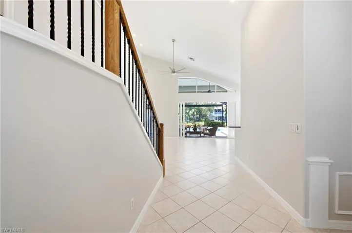 Tiled entryway featuring a staircase with wood railing