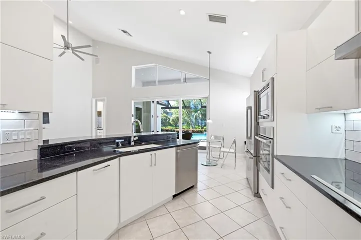 Contemporary kitchen featuring white cabinetry, black countertops, and stainless steel appliances