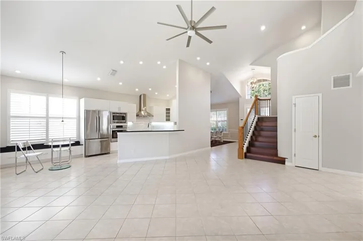 Spacious open-concept living area featuring a vaulted ceiling and tile flooring