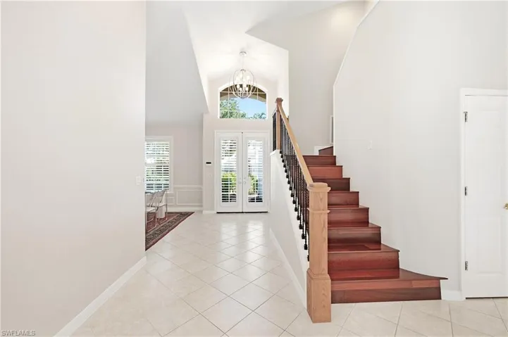 Entryway featuring a grand staircase with wood treads and a wrought iron baluster