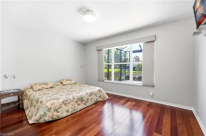 Master Bedroom featuring wood-finish flooring, a large window with a water backdrop, and a ceiling-mounted light fixture