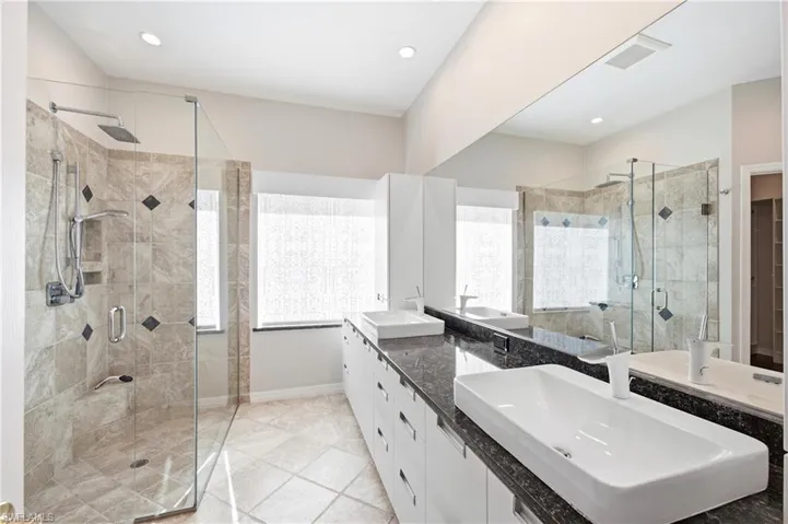 Spacious Master bathroom featuring a glass-enclosed shower with tiled walls and a rain shower head