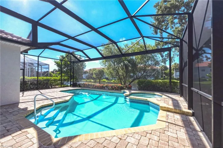Screened-in outdoor living space featuring a swimming pool, integrated hot tub, and paver decking